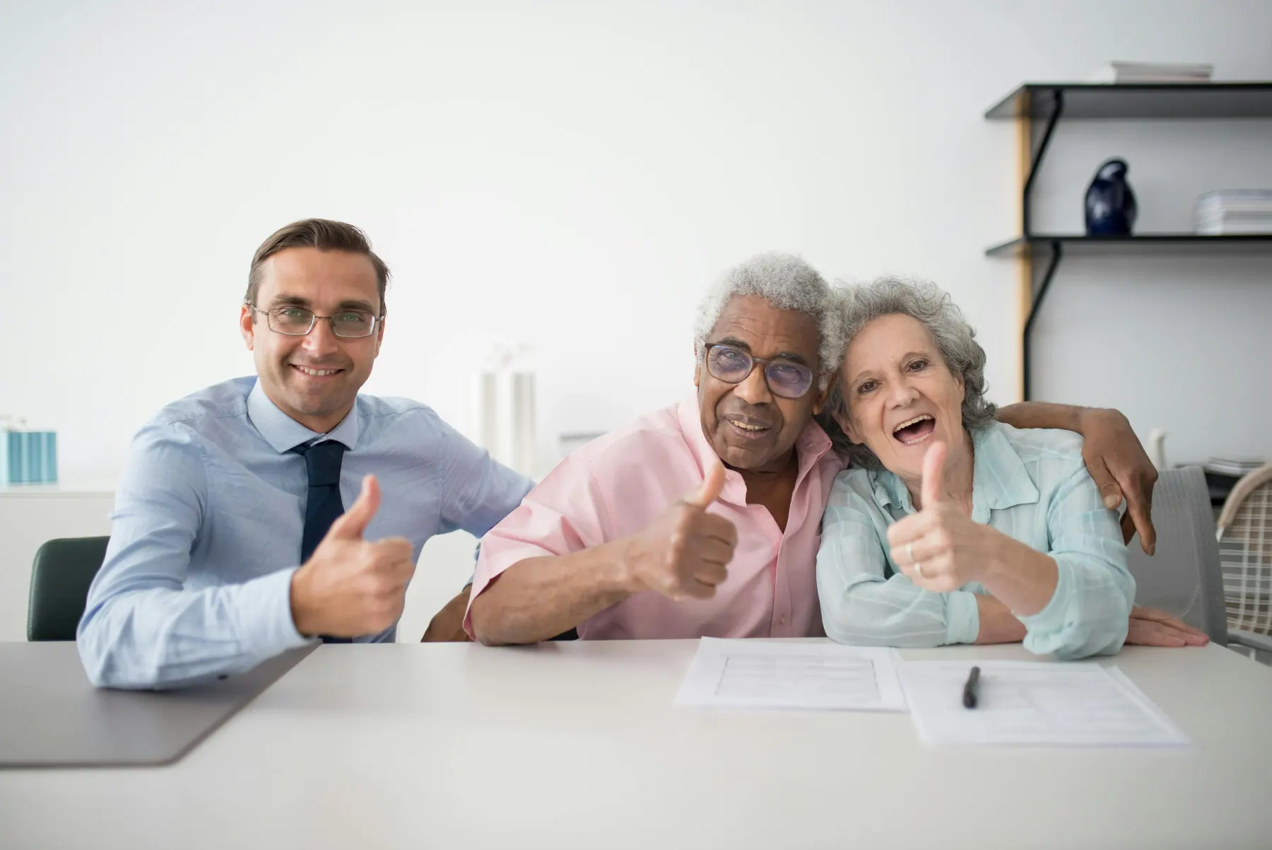 A senior couple and an advisor share smiles after agreeing on an in-home arrangement together