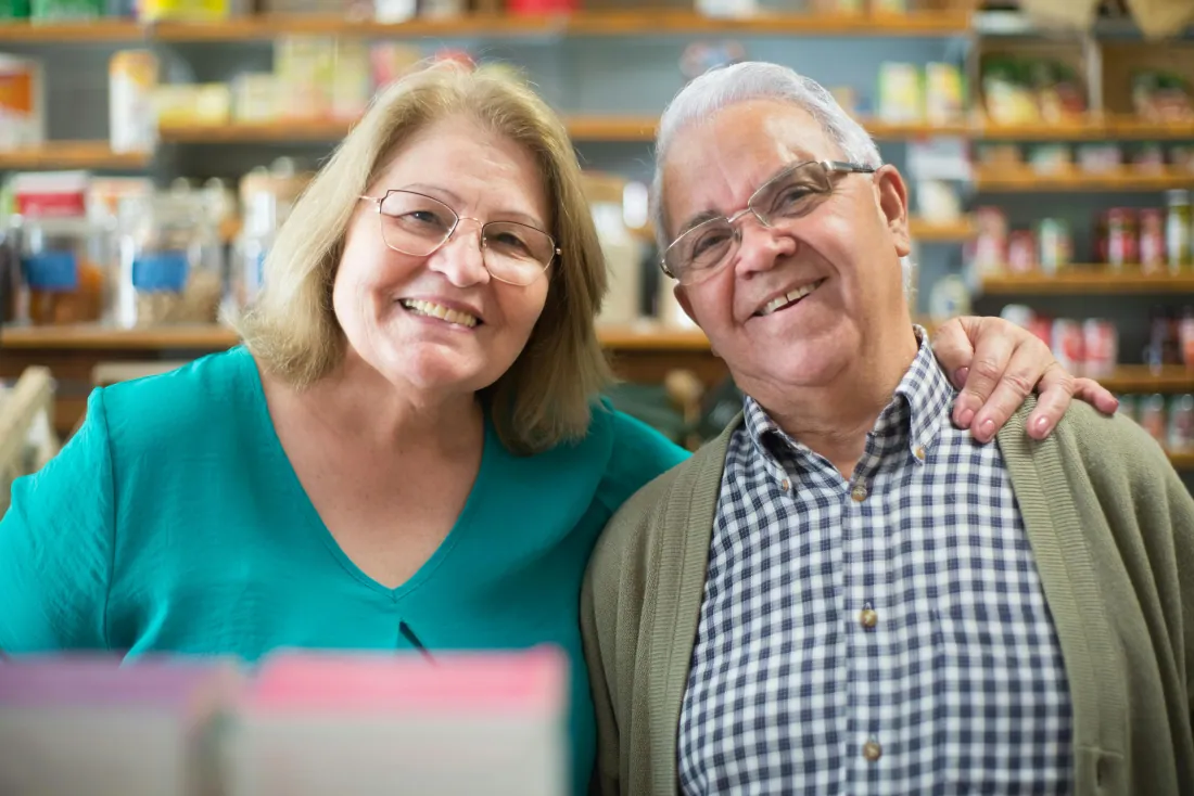 A well-dressed senior couple smile together, refined and at ease in their daily life